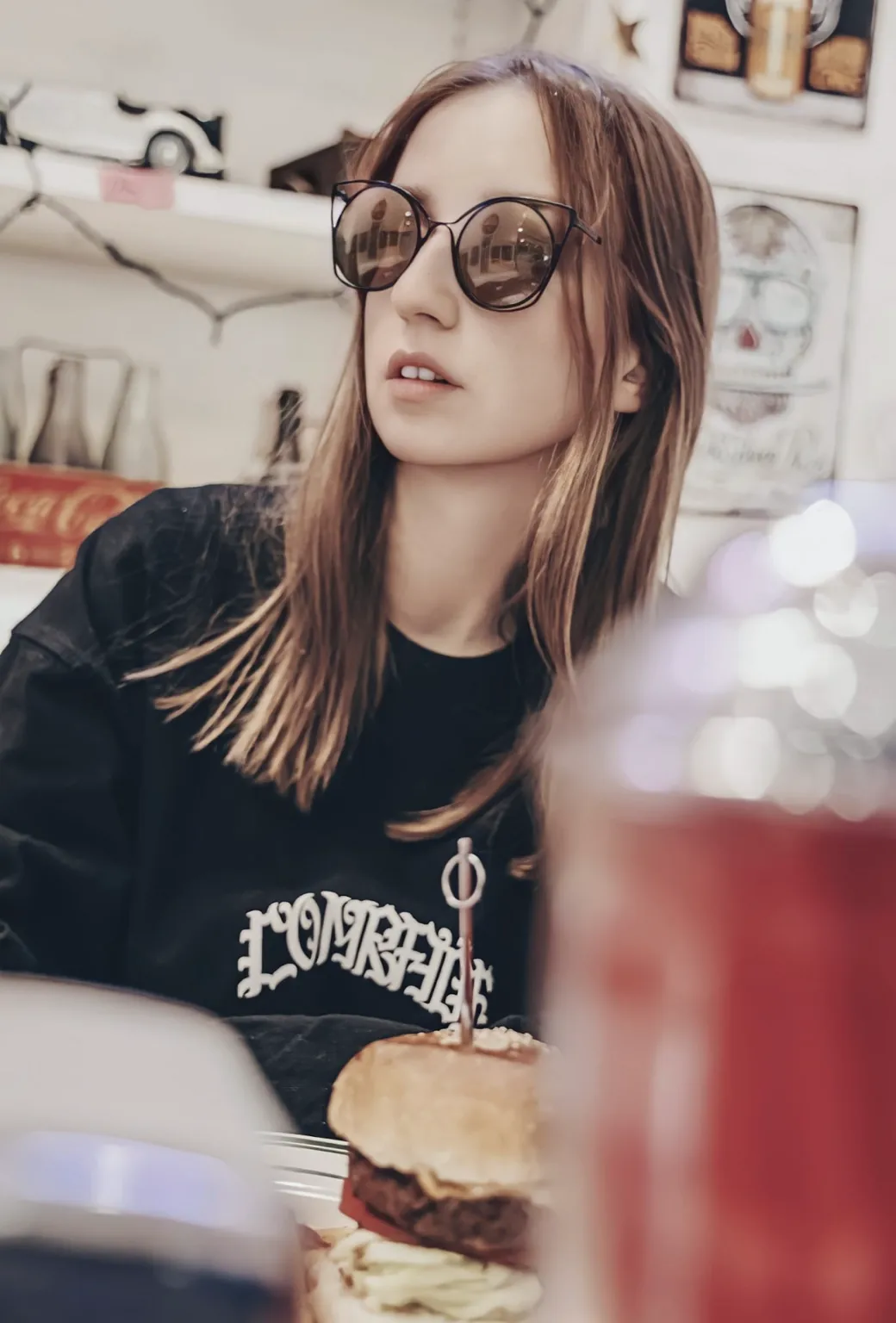赤い飲み物を持つ黒いTシャツ姿の女性