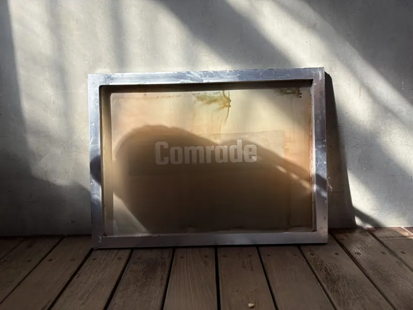 木製デッキに置かれたCOMRADEのシルクスクリーン版