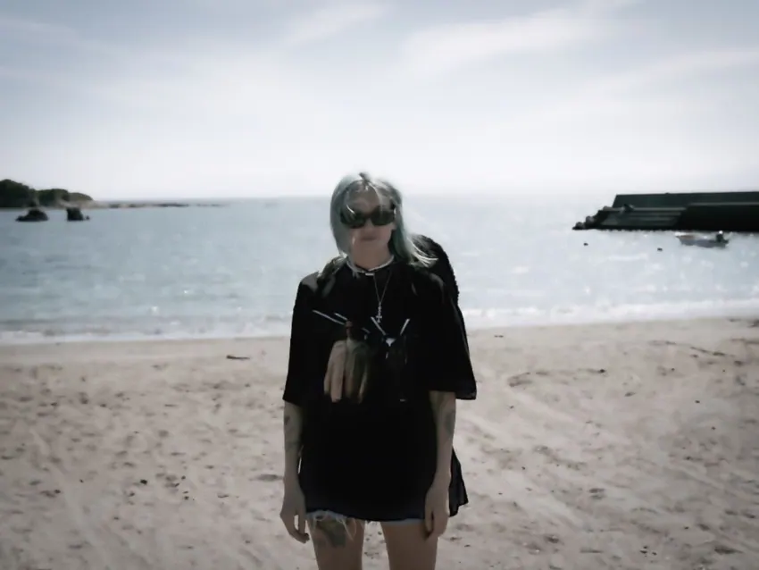 海辺の砂浜を歩く黒い服のモデル